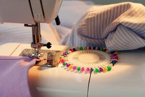 Sewing machine in use on a wooden table, stitching a light fabric in a well-lit indoor workspace photo