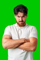 A man with a serious expression stands with crossed arms against a vibrant green background photo