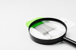A magnifying glass and lice comb placed side by side on a clean white background photo