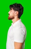 Profile view of a man with a beard wearing a white polo shirt against a bright green background photo