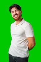 A smiling young man with a beard poses against a bright green background photo