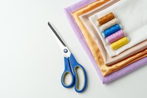 Colorful sewing threads and scissors placed next to folded fabrics in a craft workspace photo