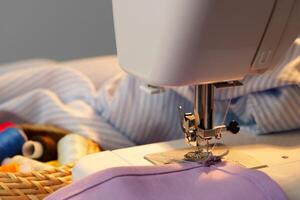 Sewing machine in use on a wooden table, stitching a light fabric in a well-lit indoor workspace photo