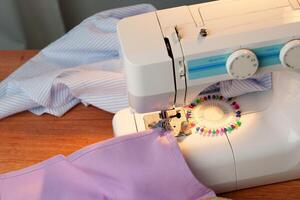 Sewing machine in use on a wooden table, stitching a light fabric in a well-lit indoor workspace photo