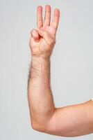 Hand gesture indicating the number three against a plain background photo