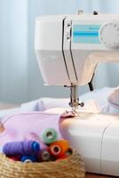 Sewing machine in use on a wooden table, stitching a light fabric in a well-lit indoor workspace photo