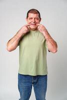 An older man smiling while making a funny face in a neutral studio background photo