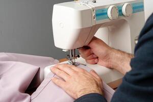 Hands sewing fabric using a sewing machine on a wooden table in a well-lit workspace photo