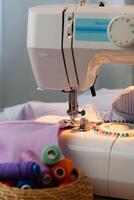 Sewing machine in use on a wooden table, stitching a light fabric in a well-lit indoor workspace photo