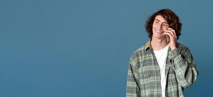 Modern communications concept. Young guy speaking on cellphone against color background photo