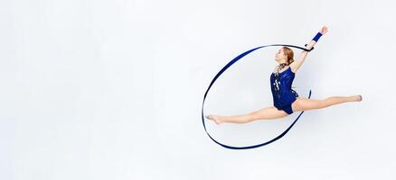 Lovely gymnast with string doing split leap in the air on white background photo
