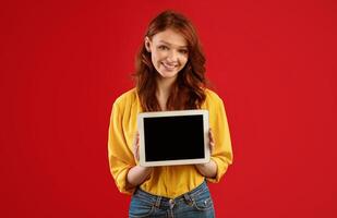 Red-Haired Student Girl Showing Tablet Computer Blank Screen Posing On Green Studio Background. Great Application. Mockup photo