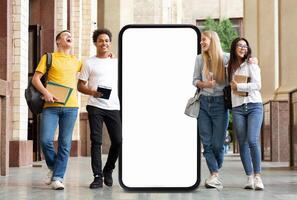 A group of four students enjoys a lighthearted moment outside a university building, passing by huge phone with blank screen photo