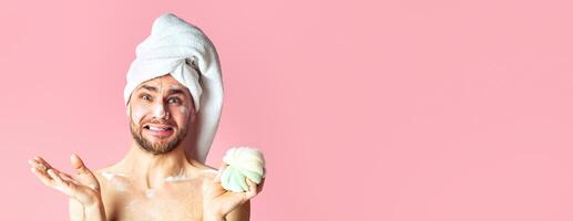 Shocked guy with towel on his head and in foam on pink background, copy space photo