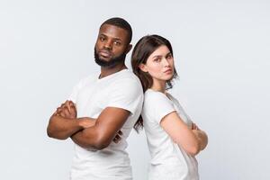 Unhappy multiracial couple standing back to back with arms crossed after conflict, having relationship problems, standing over light background photo