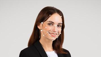 The woman stands confidently in a business suit, smiling towards the camera. Digital facial recognition points are overlaid on her face, highlighting technology's role in identity verification. photo