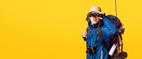 Excited male backpacker looking towards camera through binoculars over orange photo