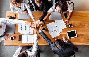 Teamwork And Unity. Business People Holding Hands Together During Corporate Meeting Sitting At Table In Office. Top View photo