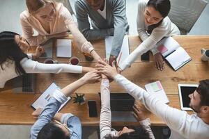 Group of people putting their hands together for united, cooperation and teamwork concept, top view photo