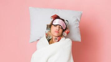 Housewife in curlers and mask, sleeps with blanket and pillow, free space photo