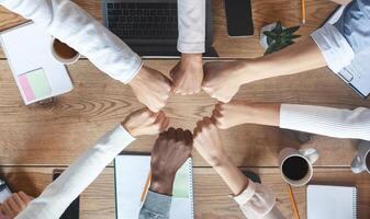 Group of international coworkers putting their clenched fists together for united, cooperation and teamwork concept, top view photo
