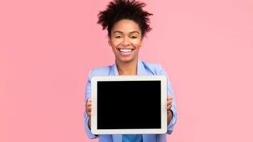 Cool App. Young afro woman showing tablet computer blank screen standing over pink studio background. Mock up, copyspace photo