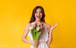 What A Surprise. Dazed Young Lady Holding Tulip Bouquet And Emotionally Gesturing In Excitement, Posing With Happy Expression Over Colorful Background photo