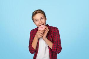 Unhealthy Sweets. Portrait Of Brother And Sister Eating Sugary Donuts And Looking At Camera, Posing Over Blue Background With Free Space photo