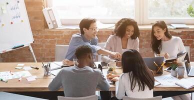 Friendly multiethnic business team sitting around table, having meeting in office photo
