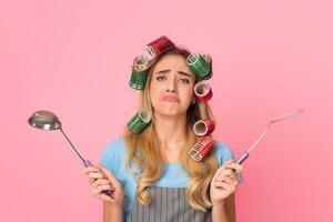 Terrible cooking concept. Sad girl spreads arms to sides, holds spatula and ladle photo