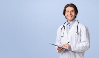 Health Insurance. Portrait Of Young Friendly Doctor With Medical Chart In Hands Posing Over Light Studio Background, Smiling At Camera, Copy Space photo