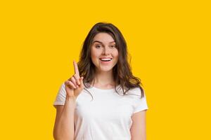 Young Woman Having Idea, Pointing Finger Up, Found Problem Solution, Posing Over Yellow Studio Background With Free Space photo