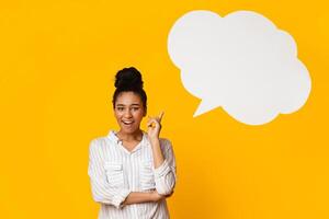 Idea Concept. Happy Afro Woman Raising Finger, Posing Over Yellow Background With Empty Speech Bubble Above Her Head, Panorama With Free Space photo