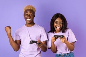 Fun hobbies concept. Cool black guy playing games with his girlfriend on lilac background. Panorama photo