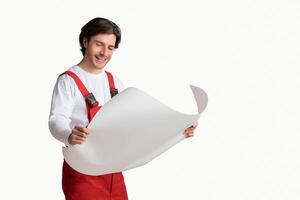 Young Repairing Worker Checking Blueprint, Holding Project Plan In Hands And Smiling, Posing Over Light Studio Background, Panorama With Free Space photo