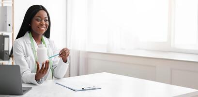 Smiling black dietologist explaining patient how to use pills, empty space photo