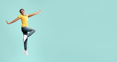 Positive African American Lady Jumping Posing Over Blue Studio Background. Full Length, Free Space photo