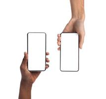 Closeup of female and male hands holding 2 smartphones with white empty screen, showing using devices, transfer data, sharing media. Two vertical gadgets with copy space, mock up, studio background photo