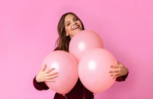Childish Mode. Playful Young Lady Cuddling Three Balloons And Sincerely Smiling, Posing Over Colorful Background With Free Space photo