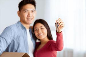 Happy korean family showing keys from their new apartment to camera, selective focus, empty space photo