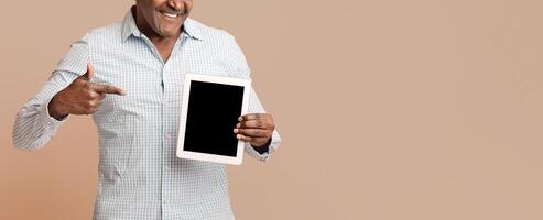 African american man showing big modern digital tablet with blank screen, orange background, empty space photo