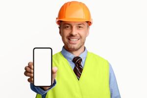 Building Services. Construction Worker Showing Cellphone Empty Screen Smiling To Camera Standing On White Studio Background. Selective Focus, Mockup photo