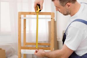 Making Furniture. Professional Carpenter Measuring Shelf With Tape Working Indoor. Selective Focus, Cropped photo