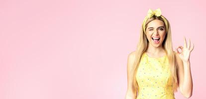 I'm Fine. Smiling blonde woman showing ok sign, winking and looking at camera isolated over pink wall, copyspace photo