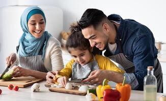 Young Arab Father Showing How To Chop Mushrooms To His Little Daughter While They Cooking Healthy Tasty Food Together At Home, Happy Muslim Family Of Three Enjoying Preparing Vegetarian Meal photo
