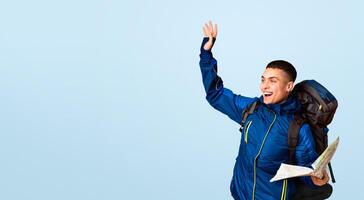 Emotional backpacker with map found a place, gesturing over orange background, looking at copy space photo