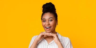 Joyful Black Girl Leaning Chin On Hands And Smiling At Camera, Posing On Yellow Studio Background With Empty Space photo