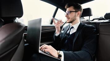 Voice Recognition, Search Technology Concept. Worker in glasses using smart phone and pc sitting in car photo