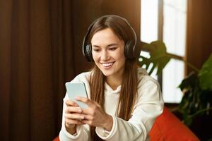 Happy girl blogger listens music and typing on smartphone photo