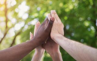 Motivated business team join hands palms together, giving high five. Successful teamwork and help support unity in common goal achievement photo